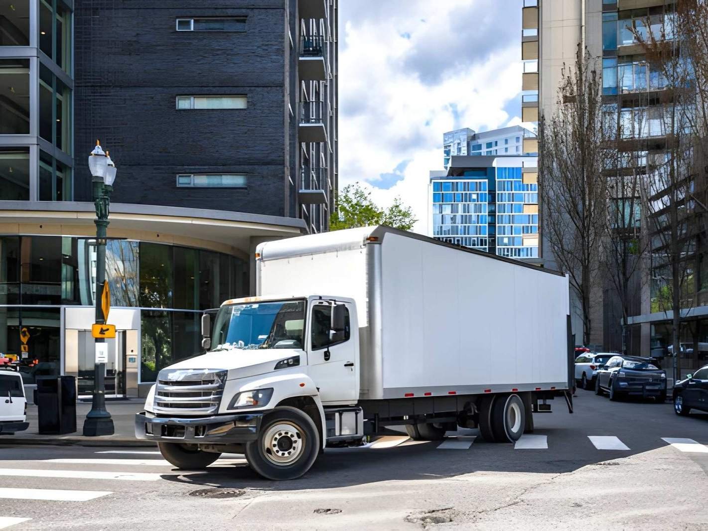 A white box truck is driving down a city street