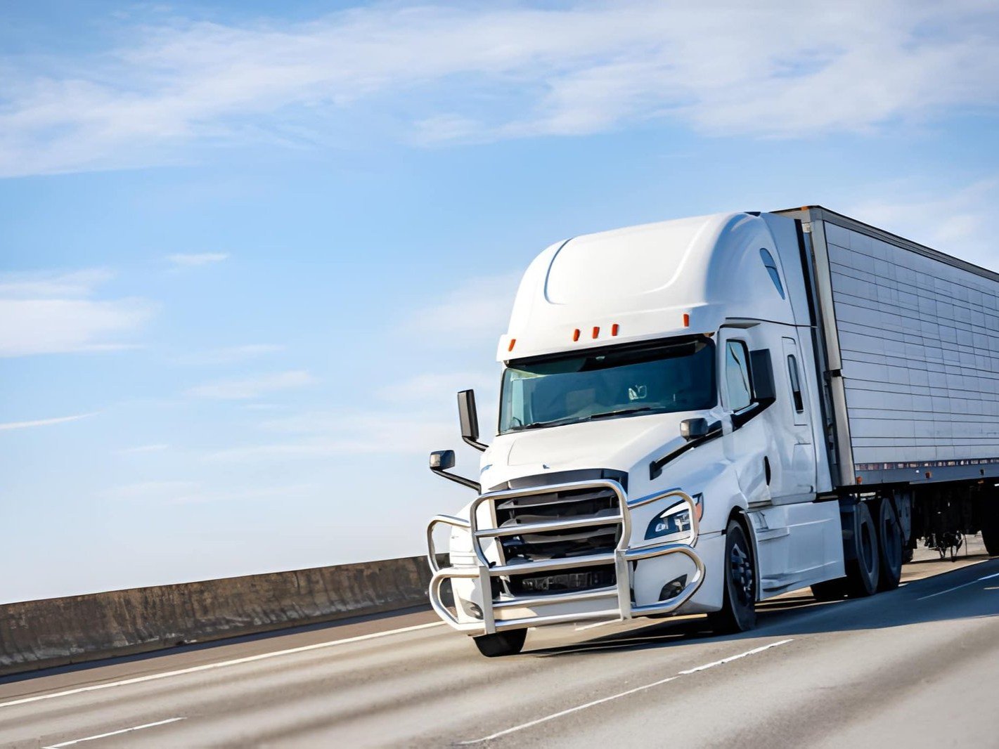A white semi truck is driving on a road
