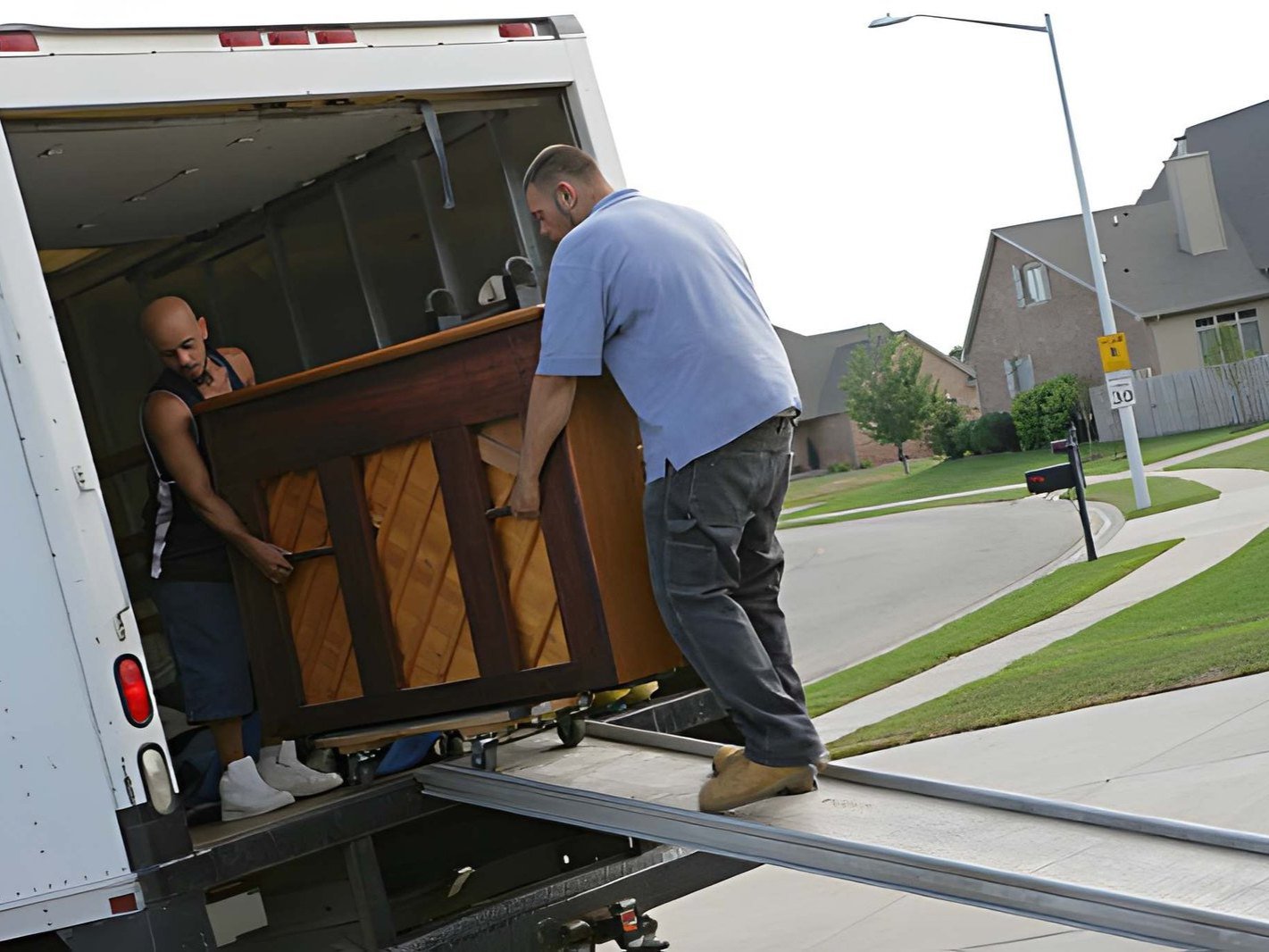 Two men are loading a piano into a moving truck